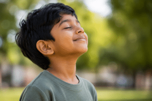 A young boy with his eyes closed and head tilted back outdoors, representative of pediatric airway dentistry in Mill Creek.