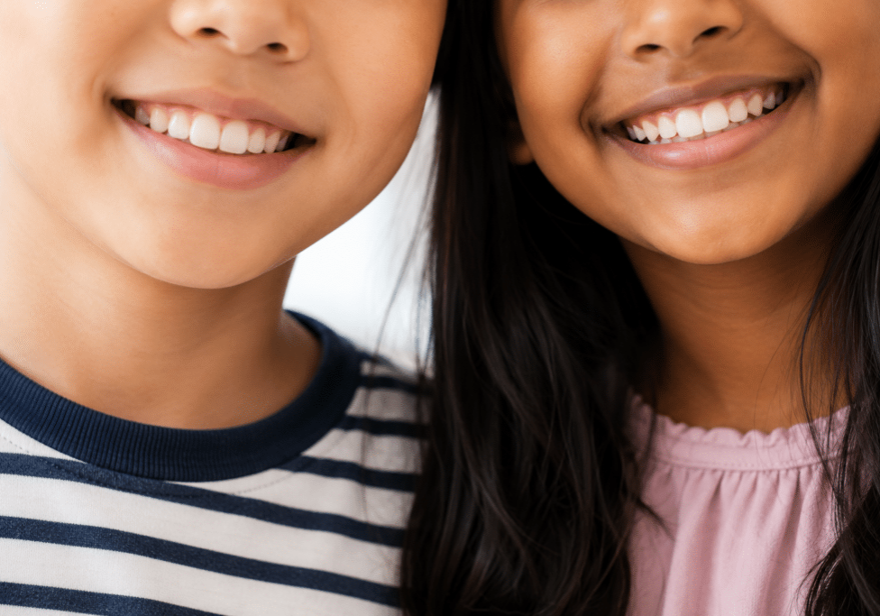 A close-up shot of two children smiling, showing their teeth during a visit for pediatric dental services in Mill Creek.